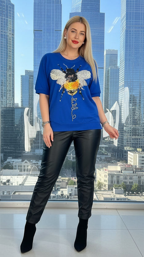 A person holding a blue handbag with a bee design.
