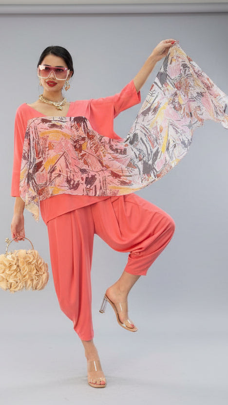Woman in a colorful outfit with a handbag, posing in front of a branded backdrop.