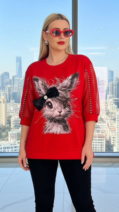 Woman wearing a red sweater with a cat design in an office setting with cityscape view
