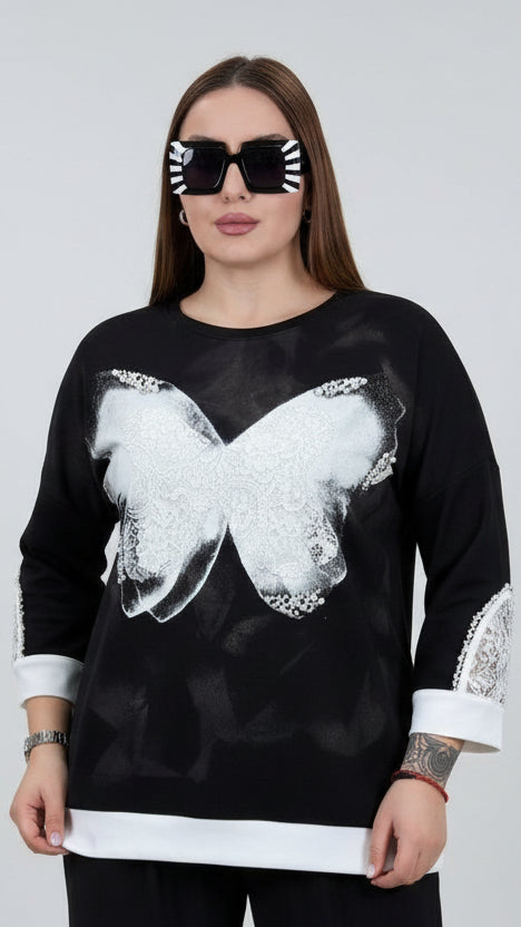 Woman taking a selfie wearing a black sweater with a white butterfly design in front of a Prada sign.