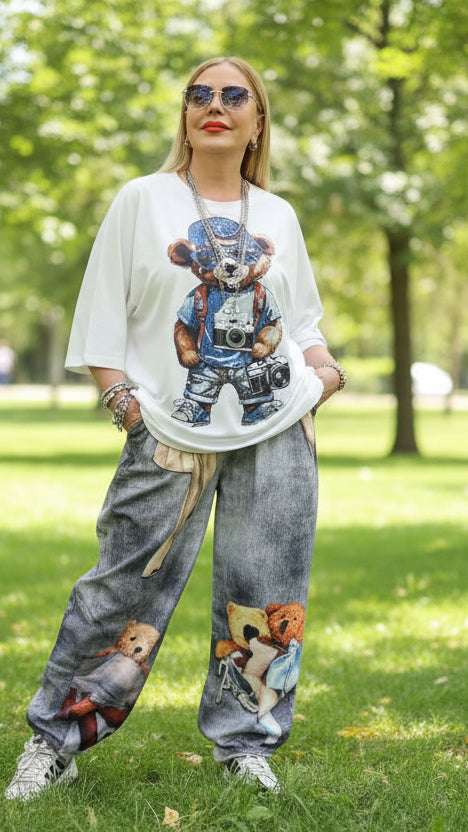 Person wearing a black t-shirt with a bear graphic and gray pants in a store setting.