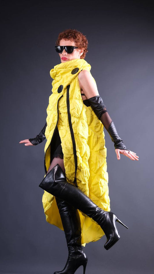 Person wearing a bright yellow puffer coat with black accents on a dark background