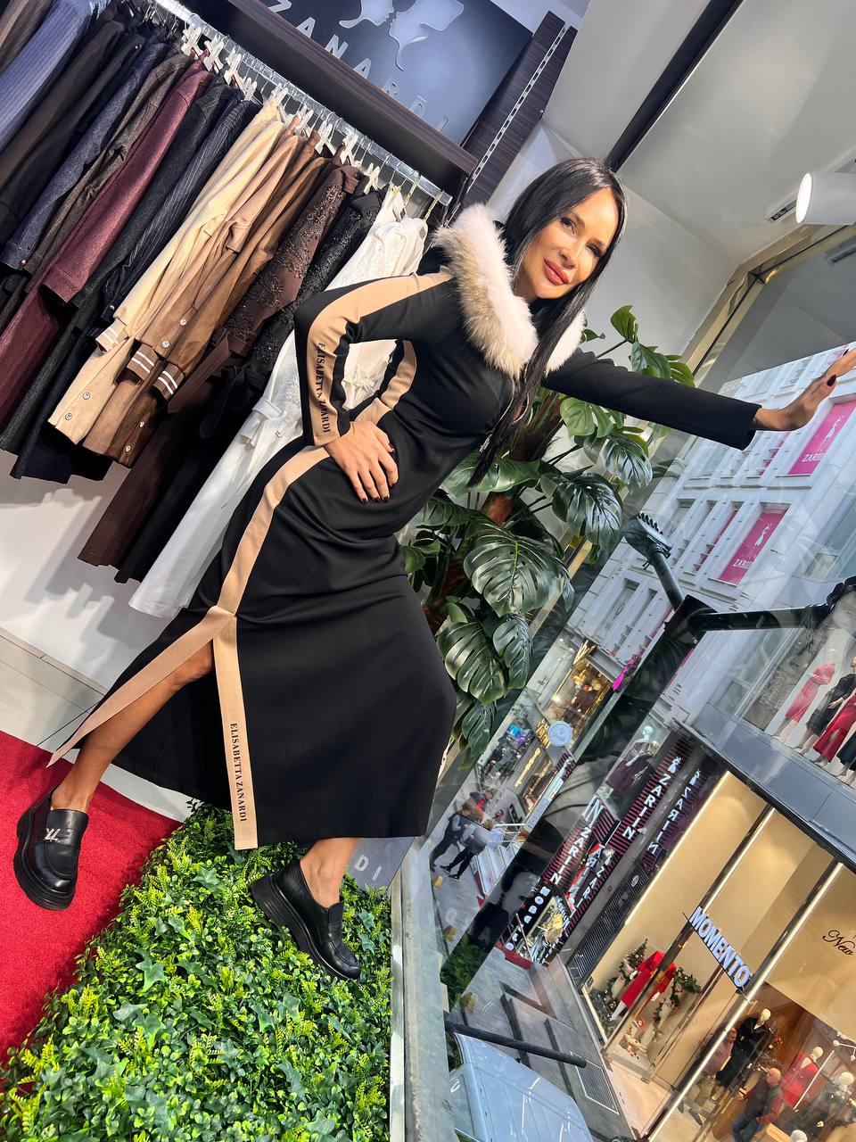 Woman in a black dress with a fur-lined jacket in a store setting