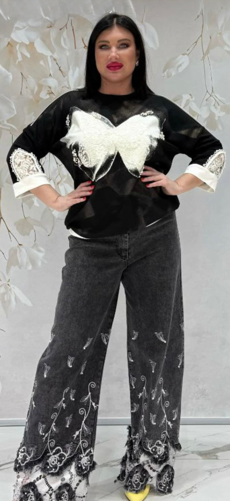 Woman wearing a black outfit with white lace details against a light gray background